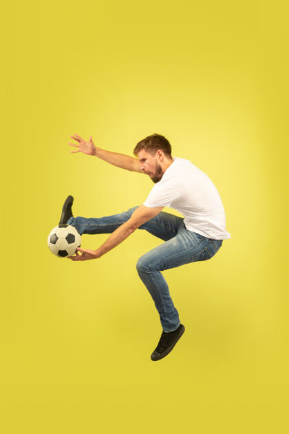 手黄色背景上孤立的快乐跳跃人的全长肖像穿着休闲服的白人男模自由选择 灵感 人类情感概念在奔跑中踢足球运动牛仔裤活力
