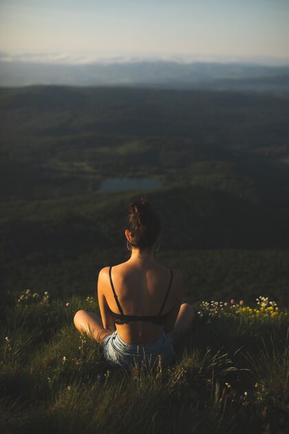 花身穿胸罩的黑发女子坐在山顶欣赏风景乡村年轻阳光