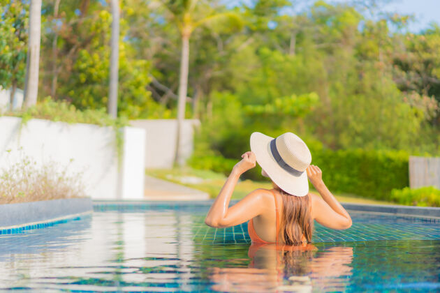 游泳池肖像美丽的亚洲年轻女子放松微笑休闲在酒店度假村的室外游泳池周围旅游度假海滩活动游泳