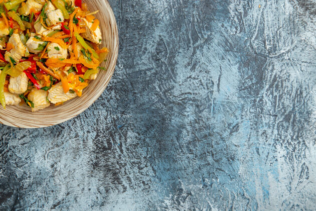 碗鸡肉沙拉的顶视图和蔬菜在光的表面新鲜菜肴午餐