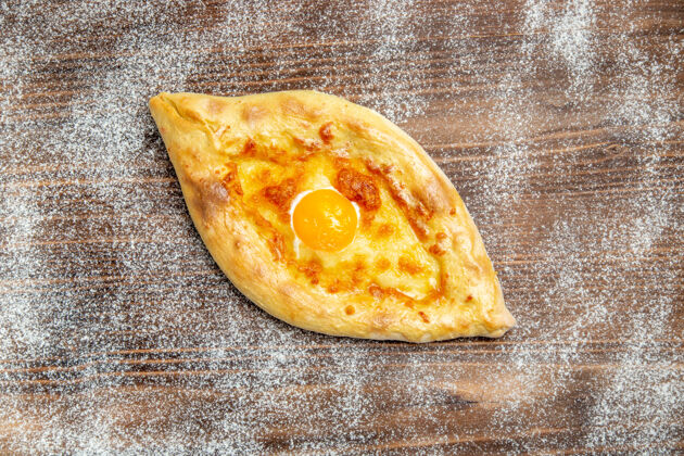 烘焙顶视图新鲜的烤面包和熟鸡蛋放在棕色的桌子上面团食物烤面包和鸡蛋顶部面包生的