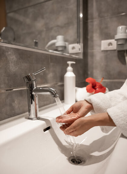 卫生一个穿着长袍的女人在自来水下洗手女性清洗浴室