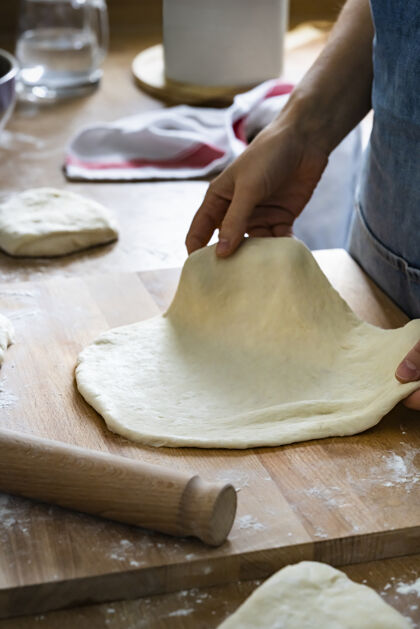 生的面包师拿着一个扁平的面团在厨房特写糕点手面团