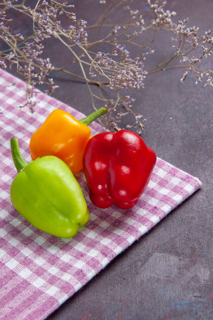 西红柿前视图彩色甜椒新鲜的甜椒在灰色的表面蔬菜辣椒辛辣的食物辛辣甜椒颜色
