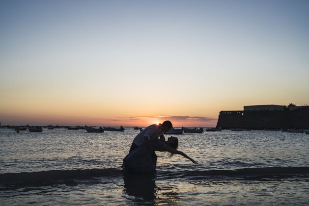 阳光一对情侣在海滩上的浪漫剪影拍摄于日落时分自然海景天空