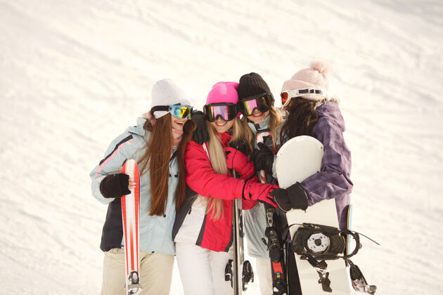 山腰女孩们手里拿着滑雪用具滑雪服上鲜艳的颜色女孩们在一起玩得很开心兴奋年轻白色