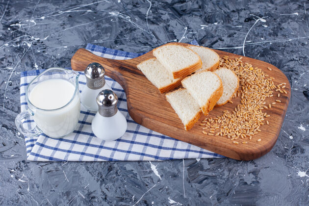 盐把切好的面包和谷物放在砧板上 旁边放着盐和牛奶 放在毛巾上 放在蓝色的桌子上毛巾美味美味