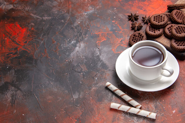 早餐顶视图一杯茶加巧克力饼干放在深色桌子上饼干茶饼干坚果和螺栓饼干浓缩咖啡