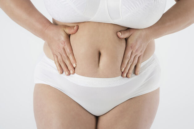 人手超重女人的特写镜头腹部胃身体护理