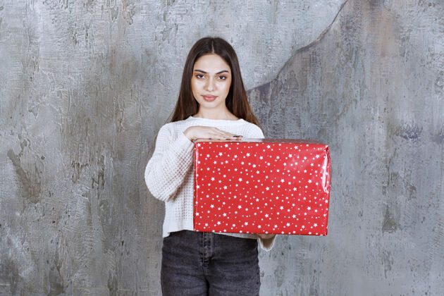 女人拿着一个有白点的红色礼盒的女人人姿势浪漫