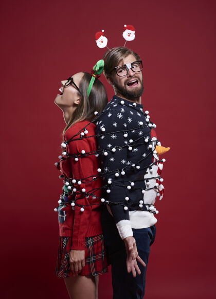 开衫一对穿着奇怪圣诞服装 系着圣诞灯的年轻夫妇圣诞节包装问题
