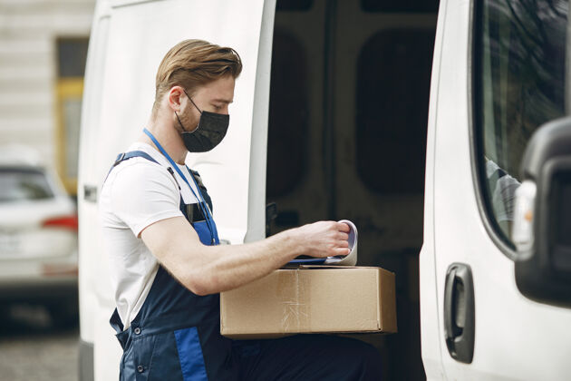手册卡车旁的人穿送货制服的人戴医用面罩的人冠状病毒概念送货员物流盒子
