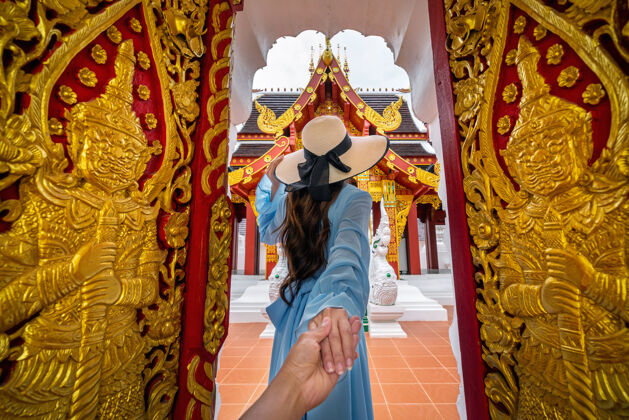人一个女人牵着男人的手 把他带到泰国清莱的瓦库阿克拉黄金泰国瓦