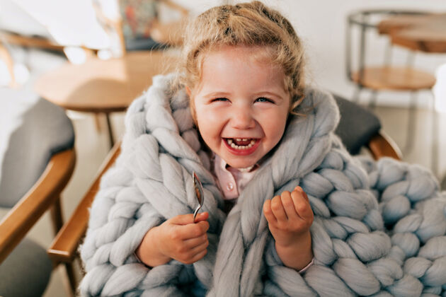 小一个穿着灰色编织格子花呢的美丽快乐的小女孩在咖啡馆休息时欢笑着孩子年轻快乐