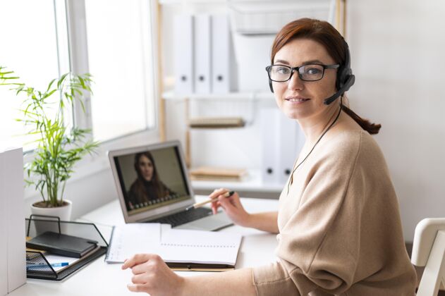 技术工作中的肖像女性在笔记本电脑上进行视频通话模型办公室耳机