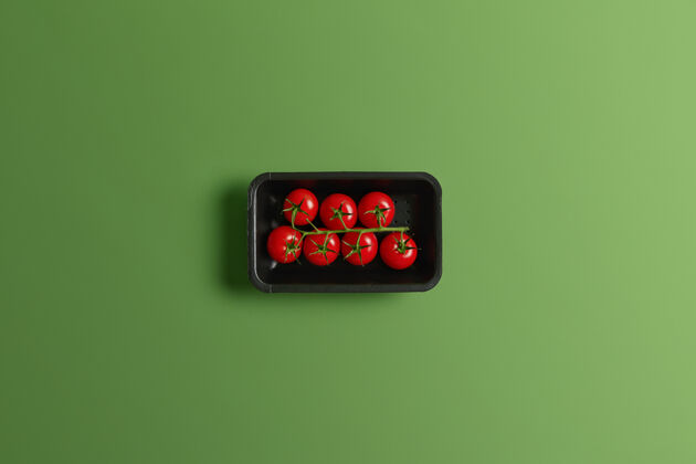 樱桃小的光滑的红色樱桃西红柿在零售包装上隔离在绿色背景上夏季时令蔬菜 甜味和酸味 高纤维和维生素c对身体健康至关重要生蔬菜包装