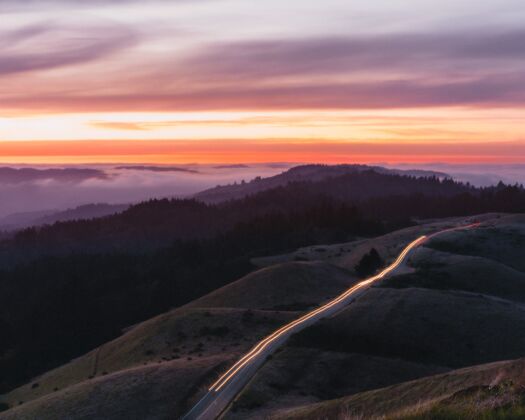 五彩缤纷的云彩道路四周群山环绕 灯光长时间照射在美丽的夕阳下线方向山
