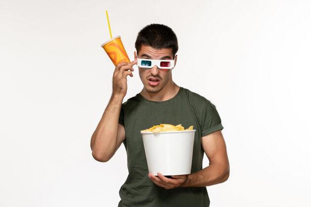杯子正面图身穿绿色t恤的年轻男性手持马铃薯cips苏打水戴着d太阳镜在白墙上拍摄电影男性孤独电影电影院咖啡苏打水土豆