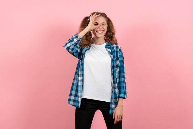 孩子正面图穿着格子衬衫的年轻女性在浅粉色背景上摆姿势年轻女性情感模特儿颜色情感人格子