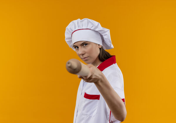 信心年轻自信的白人厨师女孩穿着厨师制服 拿着擀面杖在橘子上 留着复印空间橙色持有年轻