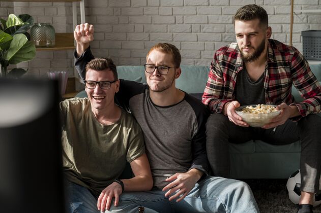 电视男性朋友在电视上看体育节目和一起吃零食的正面图啤酒瓶男电视