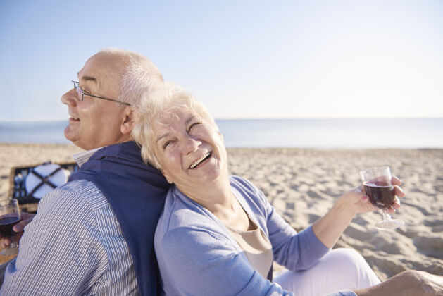 放松在沙滩上喝红酒老年夫妇在沙滩上 退休和暑假的概念休息享受丈夫