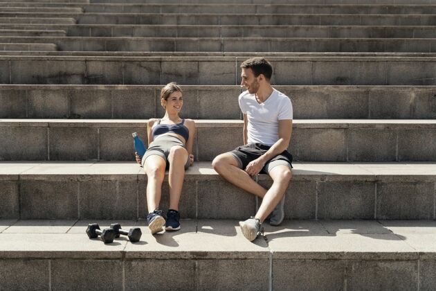 户外男人和女人在台阶上休息锻炼的正面图哑铃活动运动