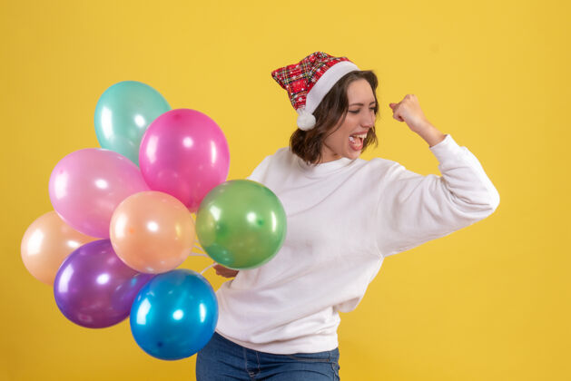 年轻女人正面图年轻女子手持五颜六色的气球站在黄色的气球情感度假区