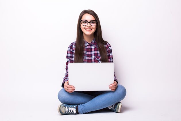 肖像拿着笔记本电脑坐在地板上的女人被隔离在白色地板上青少年地板学生