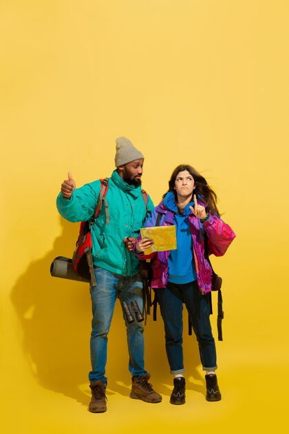 欢呼一对快乐的年轻旅游夫妇的画像 他们的包被隔离在黄色的工作室墙上乐趣五颜六色微笑