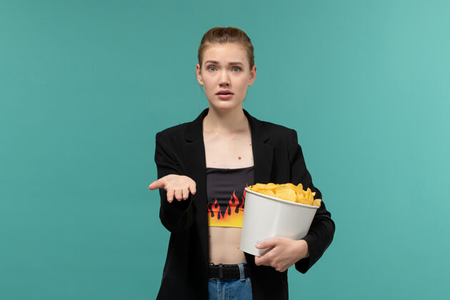 电影院正面图：年轻女性在蓝色的水面上吃薯片看电影雇员服务员电影