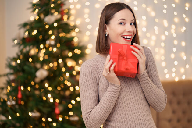 包装年轻快乐的女人红唇与包装礼品盒合影的肖像毛衣闪亮漂亮