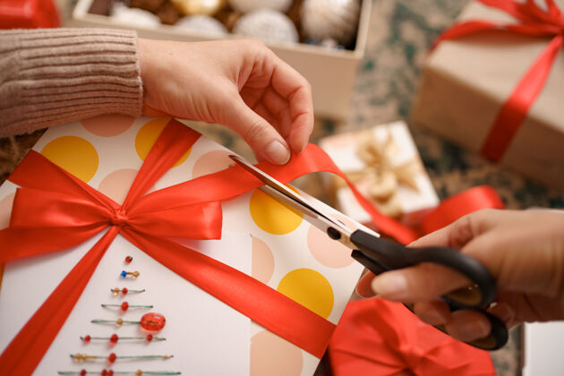 盒子女人坐在客厅里的衣柜上包装圣诞礼物圣诞球剪刀礼物