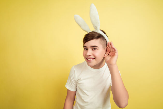 耳朵男孩像复活节兔子在黄色的工作室墙上春天兔子人类