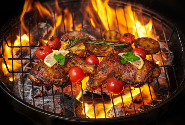 野营在火焰烤架上烤鸡腿 配上烤蔬菜 西红柿 土豆 胡椒籽 盐家禽板肉