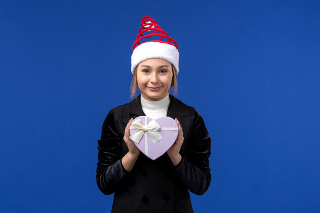 商人正面图年轻女士手持心形礼物在蓝色墙上新年情感假期领带肖像看法