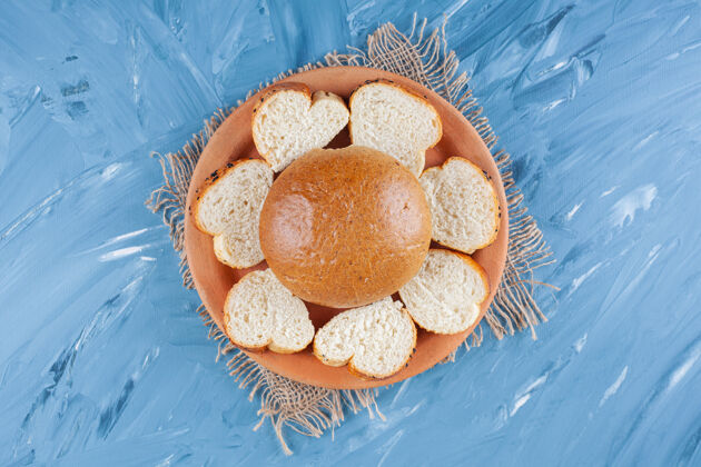烘焙面包和切片面包放在盘子里 蓝色的粗麻布餐巾上面团风味面包