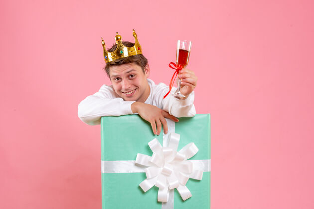乐趣正面图：年轻男性 戴着皇冠 一杯酒 背景为粉色情感五彩纸屑圣诞