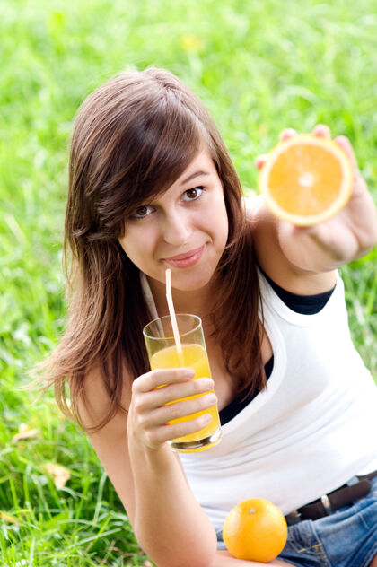 果汁拿着橘子和维生素鸡尾酒的年轻女人健康饮食腰带水果