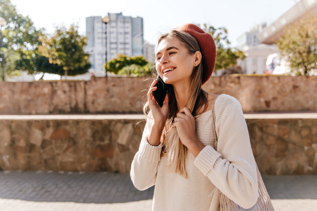 电话幽默的长发女孩在街上打电话穿着贝雷帽的白人女人在户外玩得很开心欢乐手机秋天