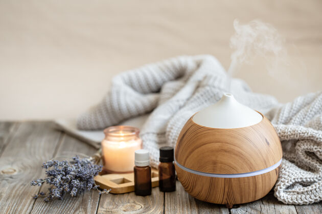 蒸汽现代芳香油扩散在木材表面与针织元素 蜡烛和薰衣草油模糊的背景芳香疗法芳香成分