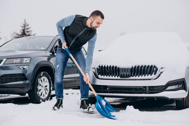人在车旁用铲子铲雪的人降雪冬天寒冷