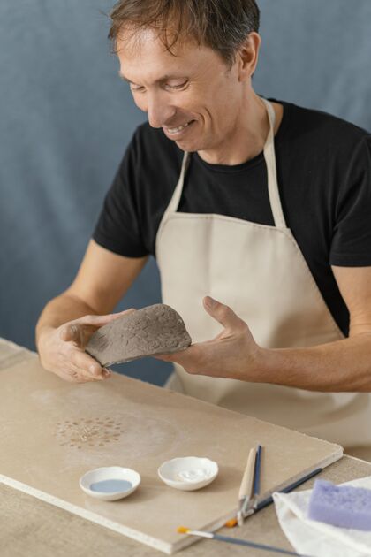 艺术家特写笑脸人做陶器垂直男性爱好