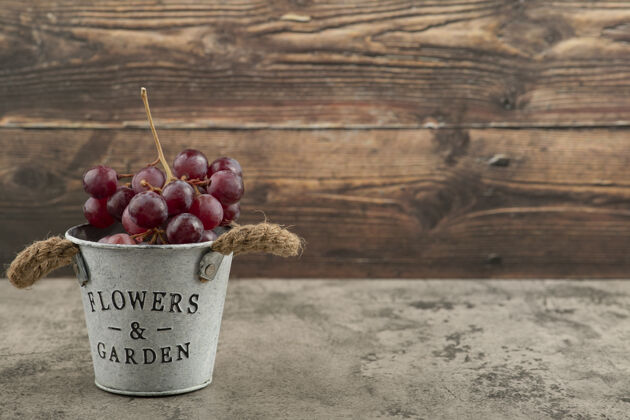 成熟大理石桌上放着一桶红色的新鲜葡萄甜新鲜明亮