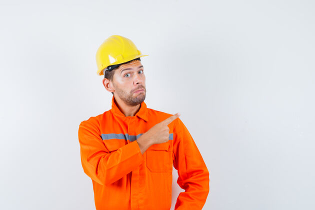犹豫建筑工人指着远处的制服 戴着头盔 神情犹豫不决 眼前一亮起重机土建承包商