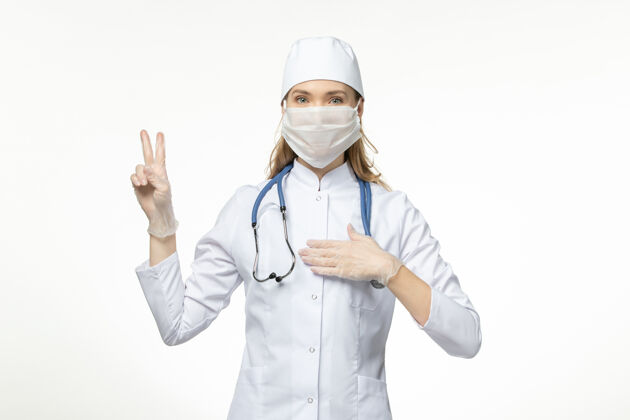 大流行前视图：穿着白色医疗服 戴着白色口罩的女医生在白色墙壁上疾病传播医务人员外套面罩