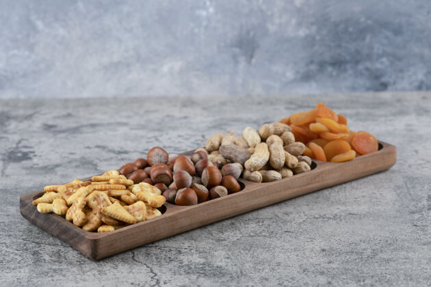 零食在大理石表面放满各种坚果 饼干和杏干的木板榛子健康什锦