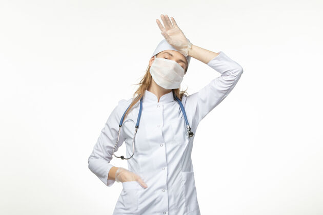 病毒正面图女医生穿着医疗服 戴着口罩和手套 因冠状病毒在淡白墙上传播疾病大流行健康冠状病毒大流行女性药品