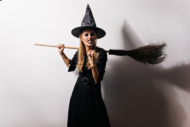 巫师愤怒的女巫在想邪恶的事情穿着黑色长裙的女巫师在万圣节表达愤怒金发恐惧邪恶