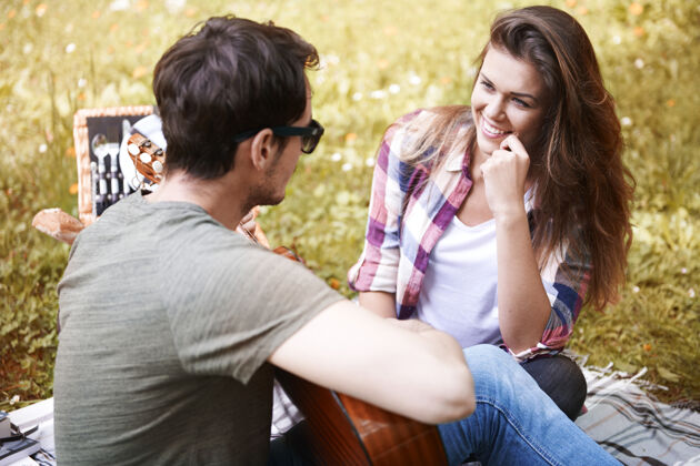 周末情侣在公园野餐男吉他浪漫的约会浪漫野餐篮草地